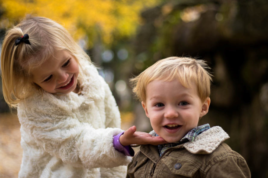 young girl holds her baby brothers chin to look at his teeth after getting dental sealants